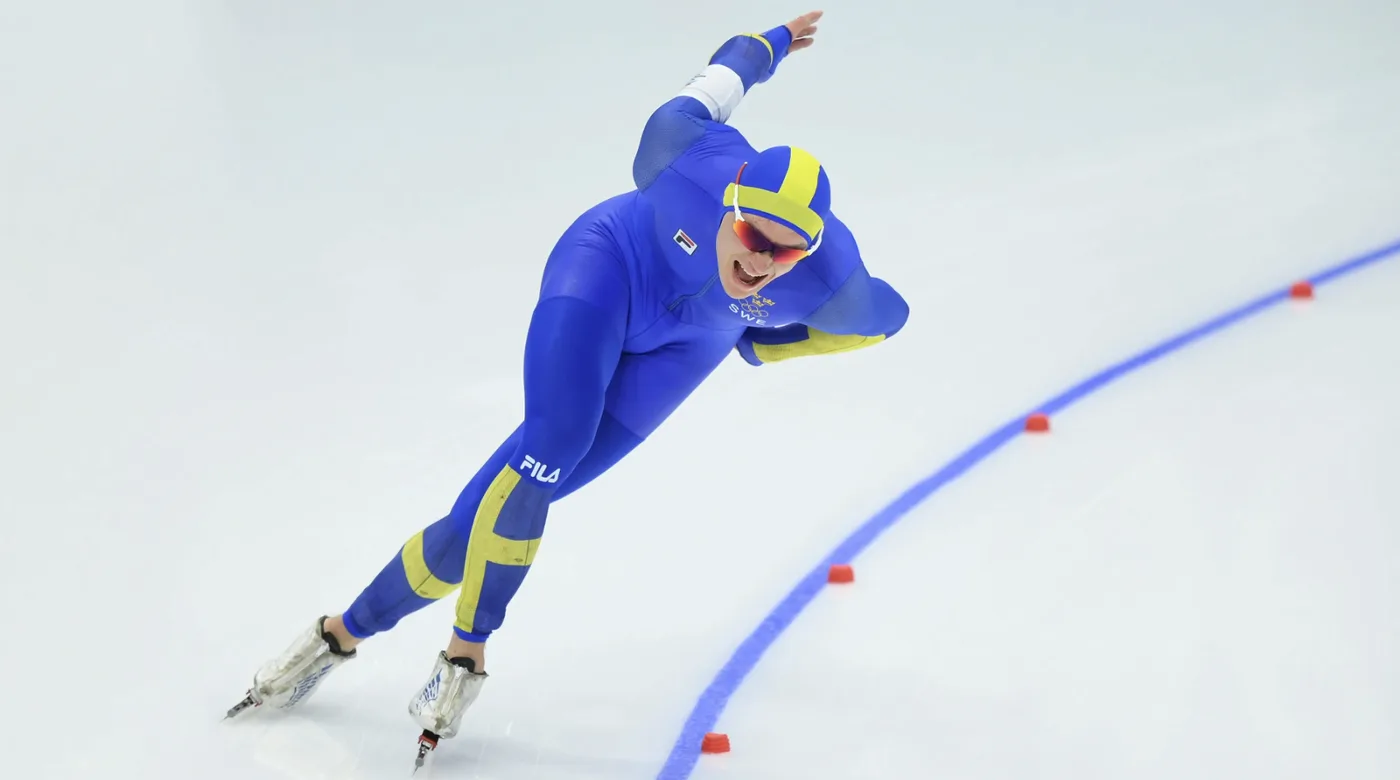 Nils van der Poel skating a bend in the Swedish team suit