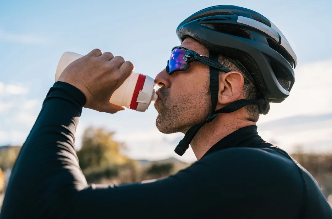 A cyclist drinking from a bottle mid-ride
